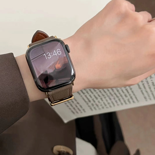 Smartwatch with a brown leather strap on a wrist, with a blurred background.